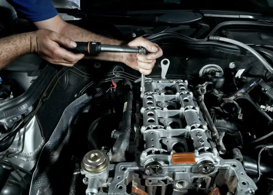 Hands tightening a bolt on an engine with a torque wrench